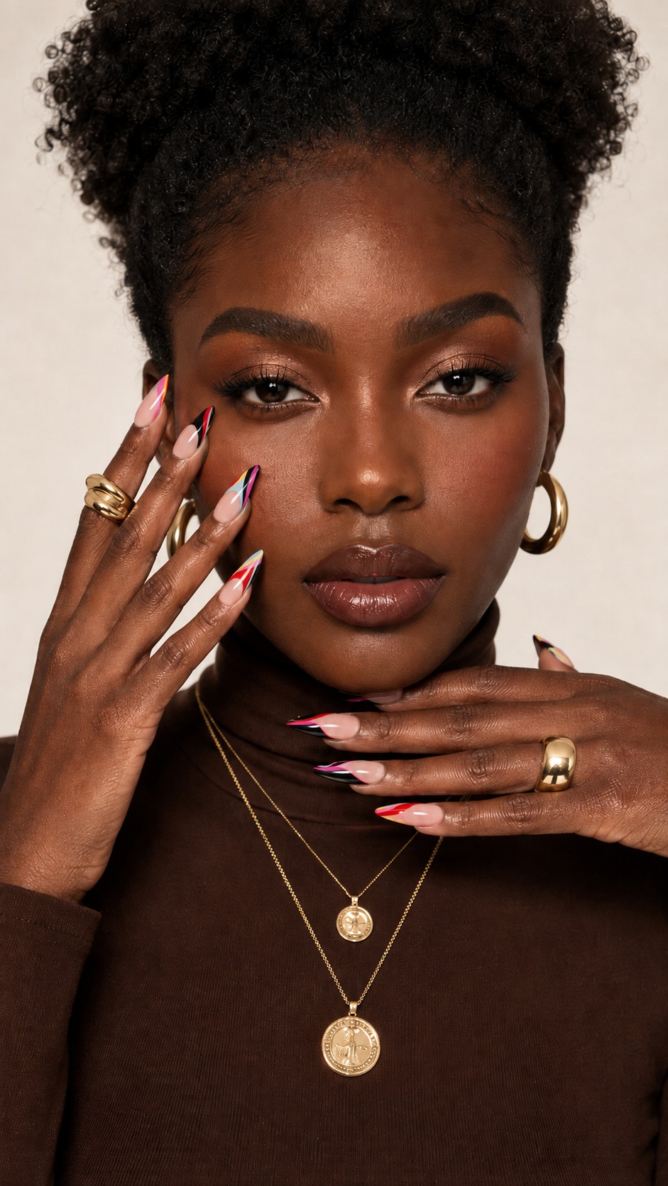 A model's hand-painted color-block press-on nails in magenta, cobalt and black, styled with gold jewelry